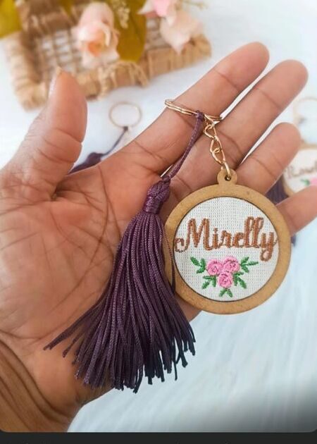 Chaveiro de bastidor bordado com o nome Mirelly e um arranjo de flores
